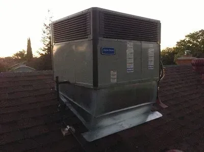 A large air conditioner is sitting on top of a roof.