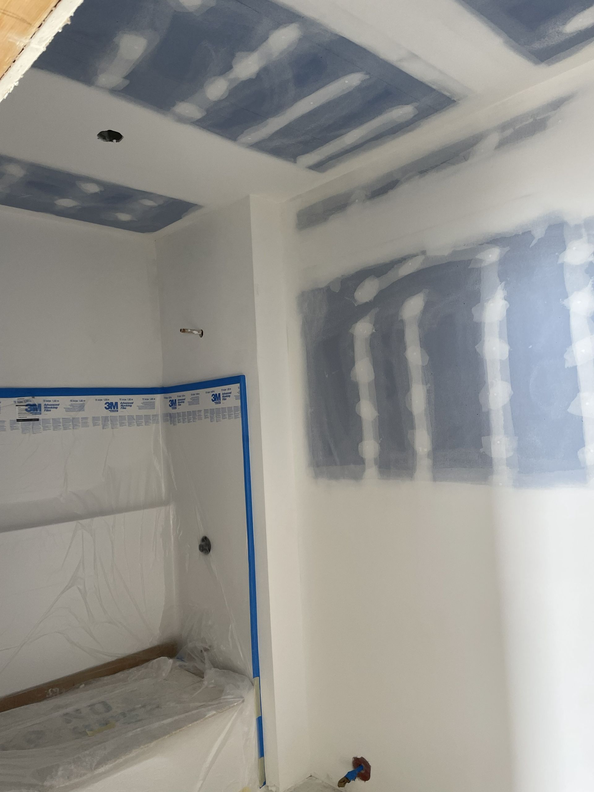 Drywalled room under renovation with taped seams and a built-in shelf niche.