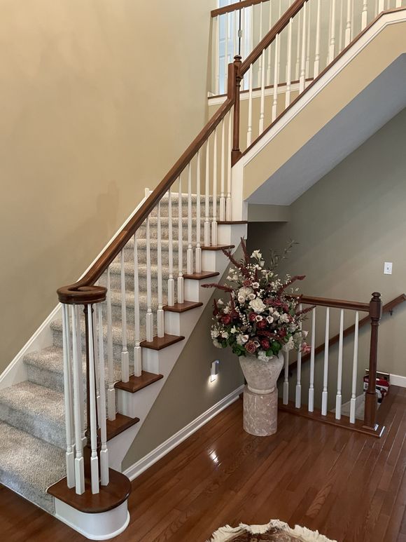 Indoor staircase with white balusters, brown wood steps, and a floral arrangement on the landing.