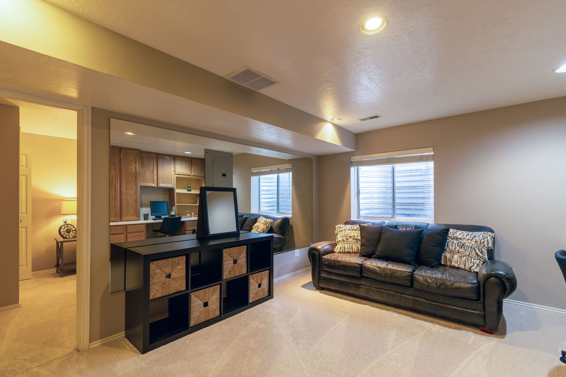 Open living room with a black sofa, cube storage, and warm recessed lighting.
