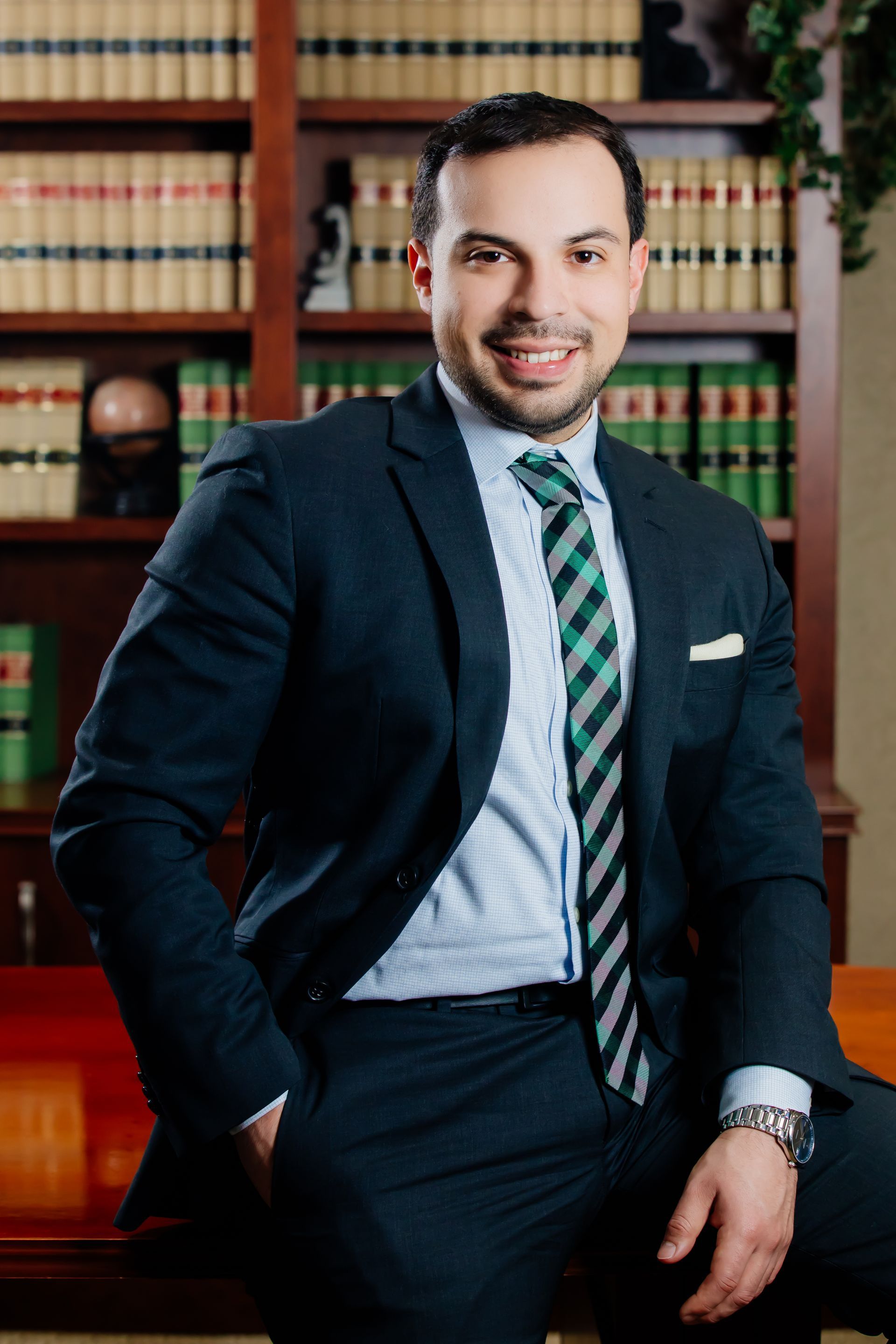 Brandon Granda smiling for photo in front of a library filled with law books