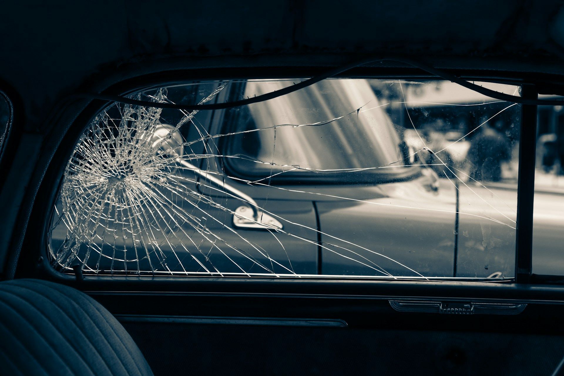 Broken car window, looking out at another car.