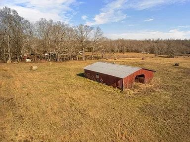 An aerial view of a red barn in the middle of a field.