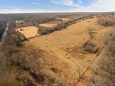 An aerial view of a large field surrounded by trees and a river.