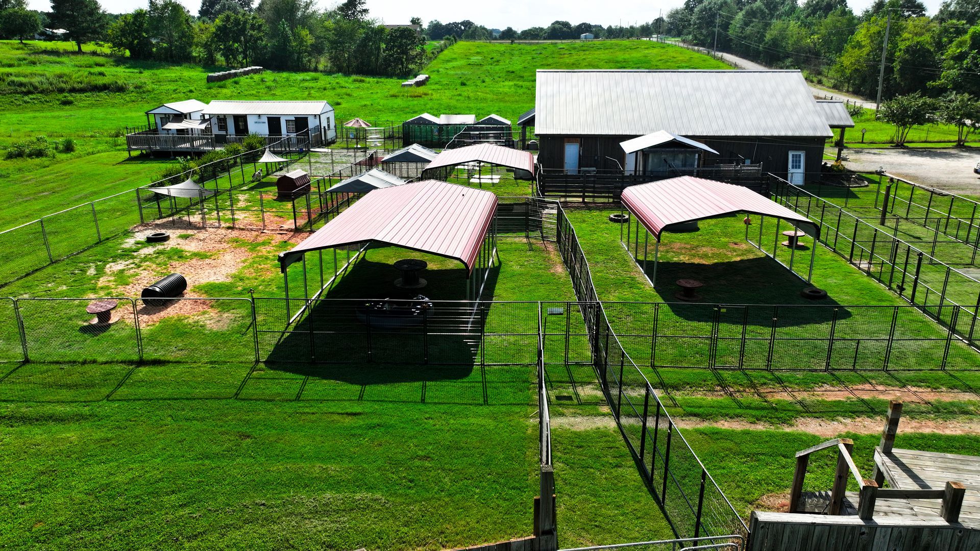 An aerial view of a fenced in area with a house in the background.