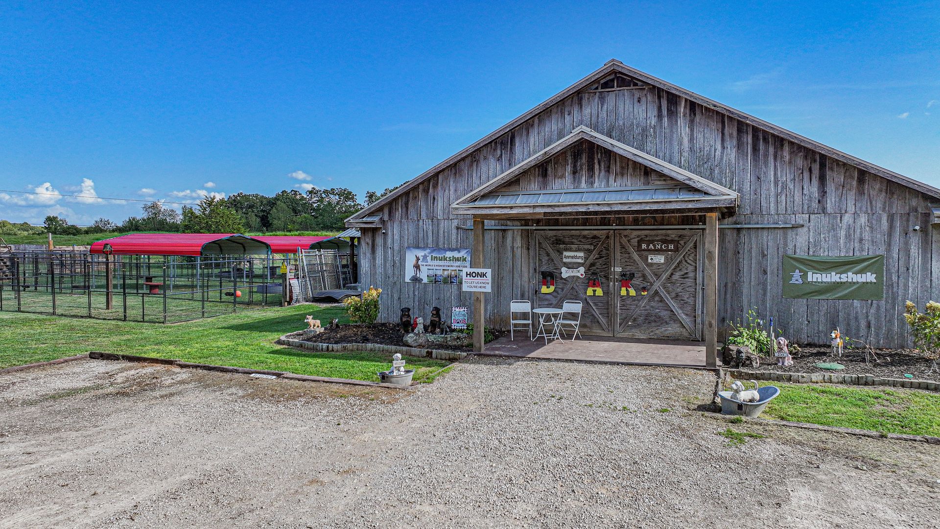 A large wooden barn is sitting in the middle of a grassy field.