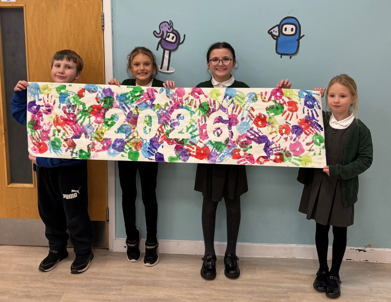 A group of young children holding a 2026 banner.
