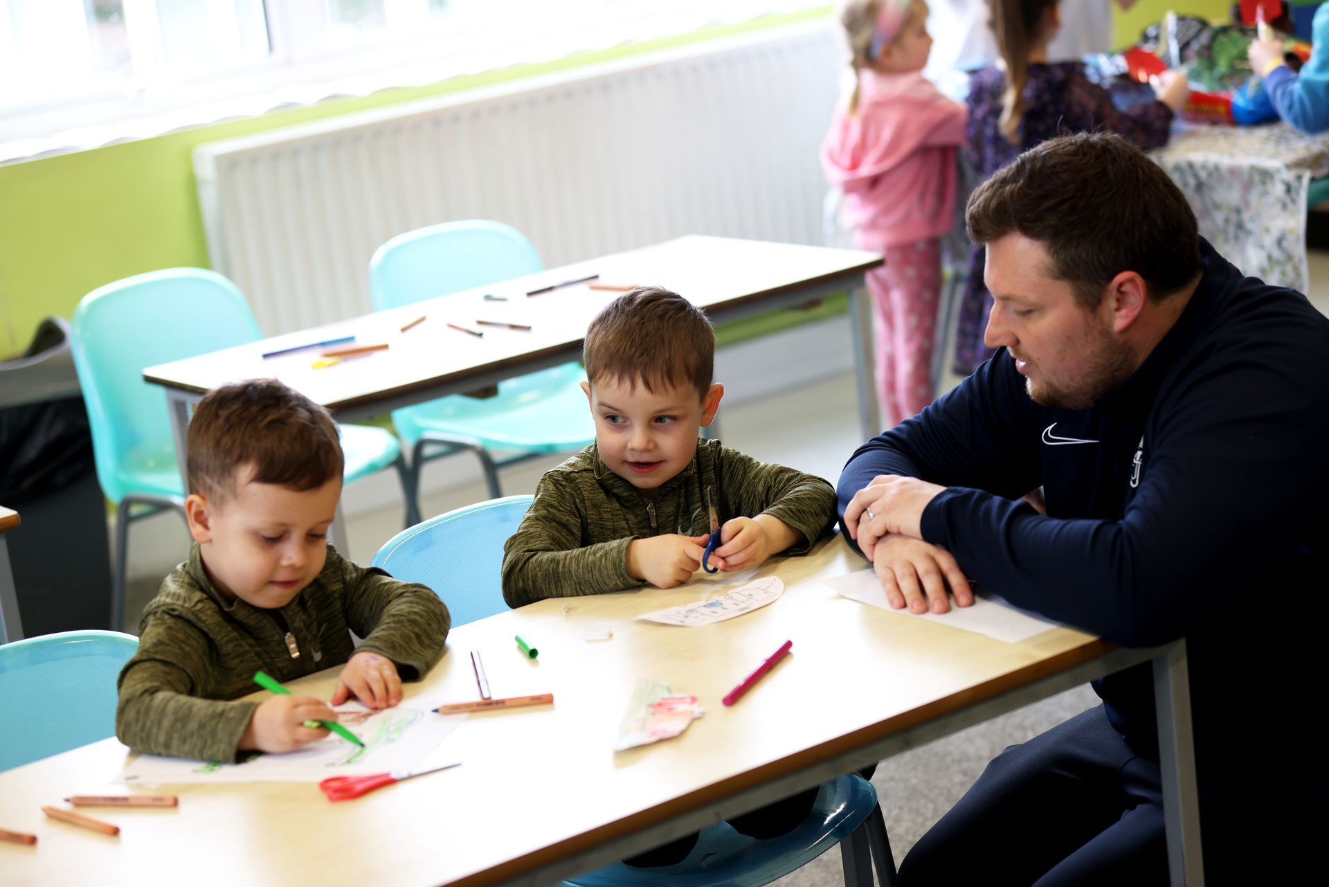 A man is sitting at a table with two young boys.