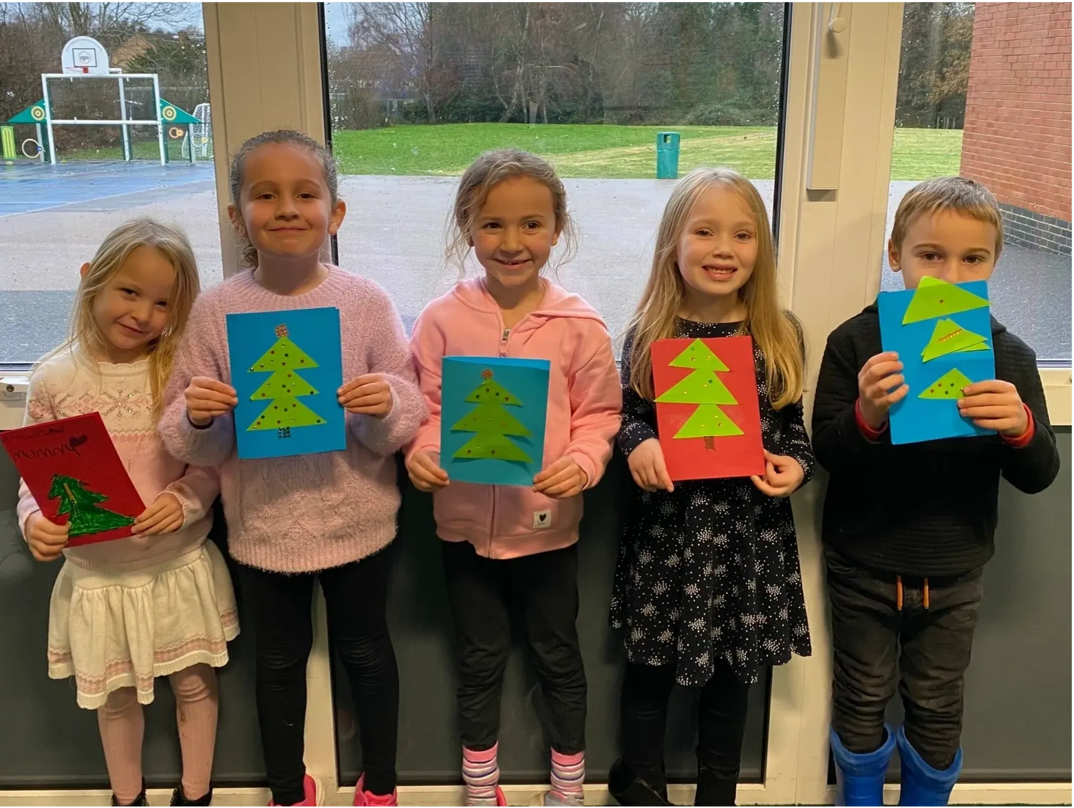 A group of children are standing next to each other holding christmas cards.