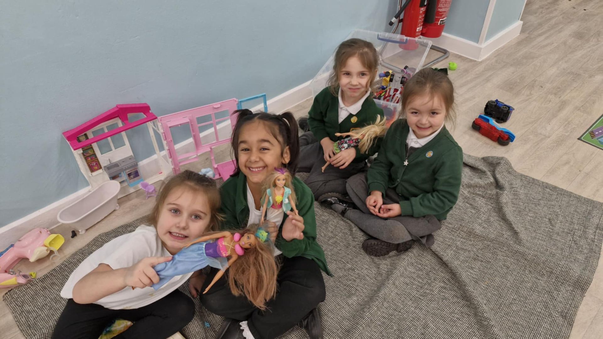 Three young girls are playing with snow in a classroom.