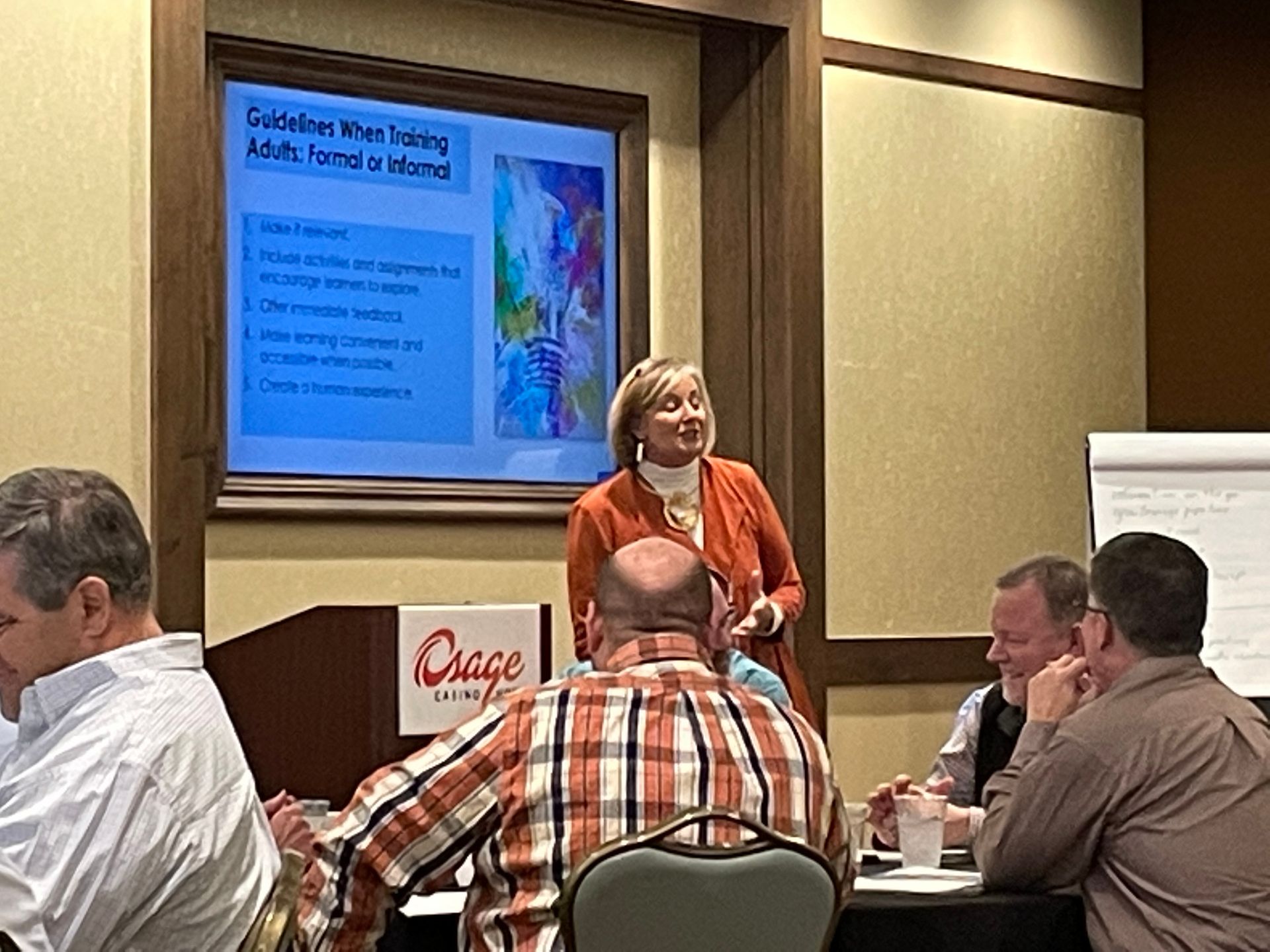 A woman is giving a presentation to a group of people in a room.