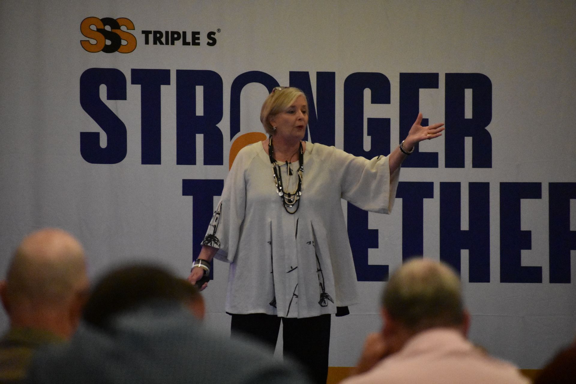 A woman stands in front of a sign that says stronger together