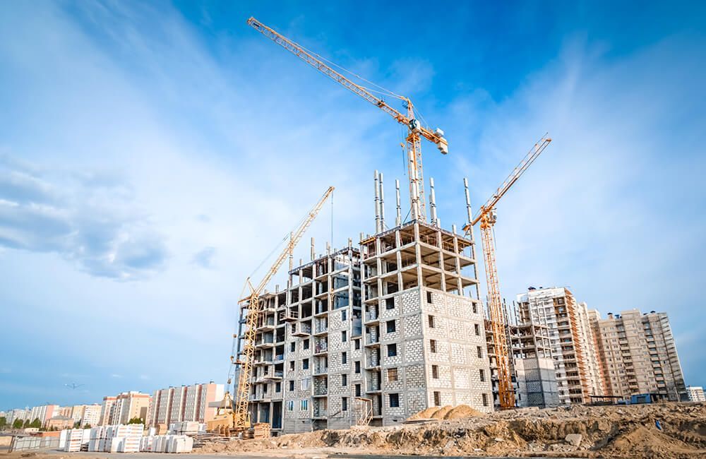 A large building is being built with cranes and a blue sky in the background.
