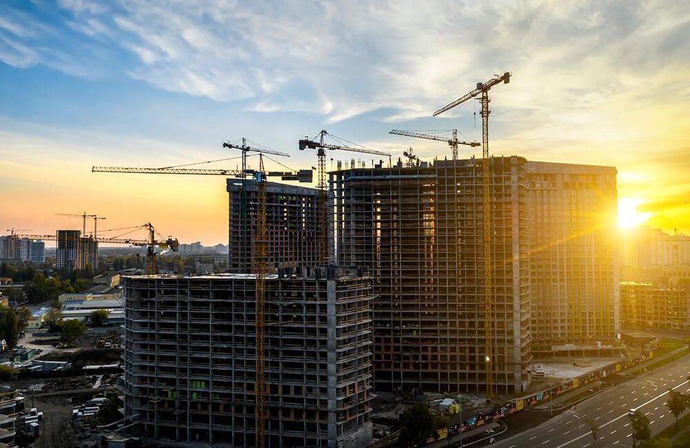 An aerial view of a building under construction in a city at sunset.