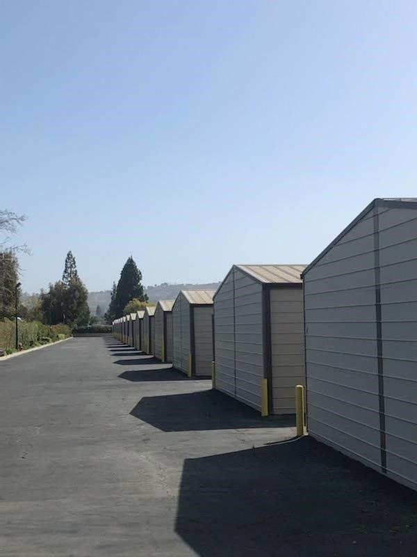 Row of beige storage units along a paved road under a blue sky.Cash