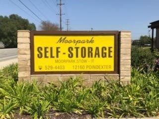 Sign for Moorpark Self-Storage; yellow background with brown text, brick pillars. 12160 Poindexter address.