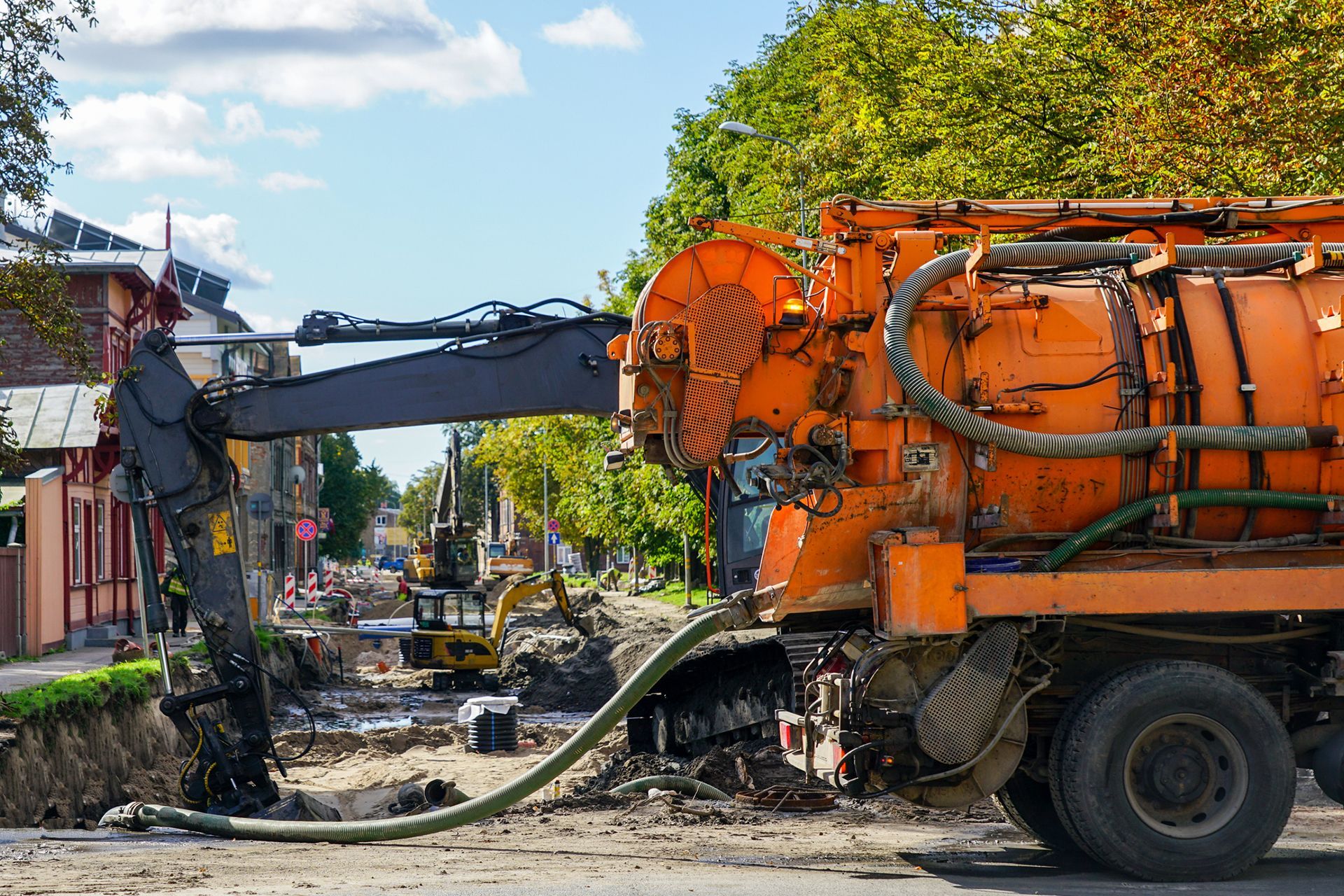 Hydrovac truck with combined vacuum suction and canal jetting machine on city street rebuild.