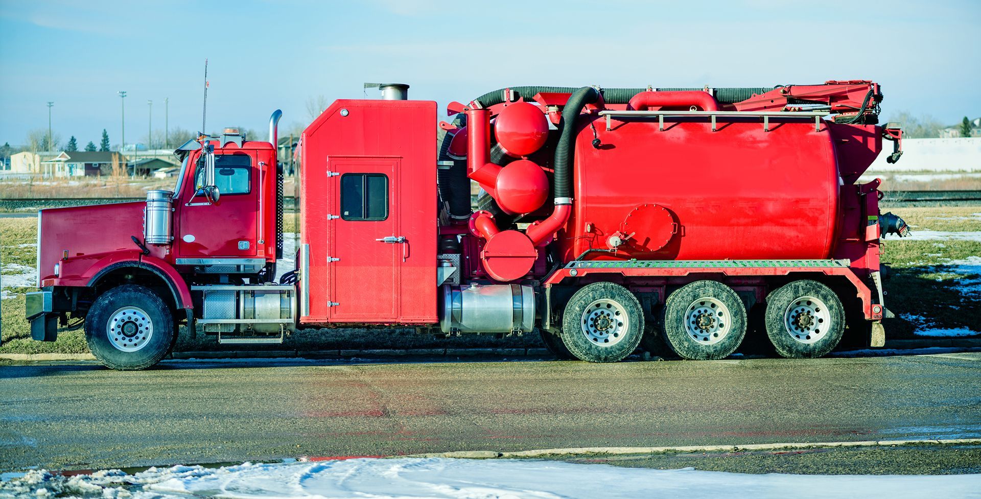 Red Hydrovac truck parked on the road, ready for vacuum excavation.
