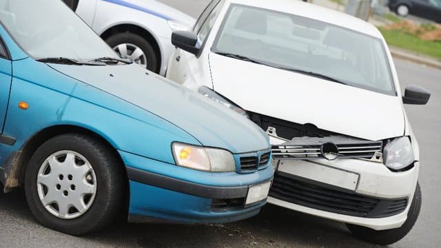 Ein blaues und ein weißes Auto sind in einen Autounfall verwickelt.