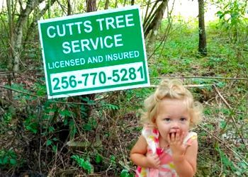 A little girl is standing in front of a cutts tree service sign.