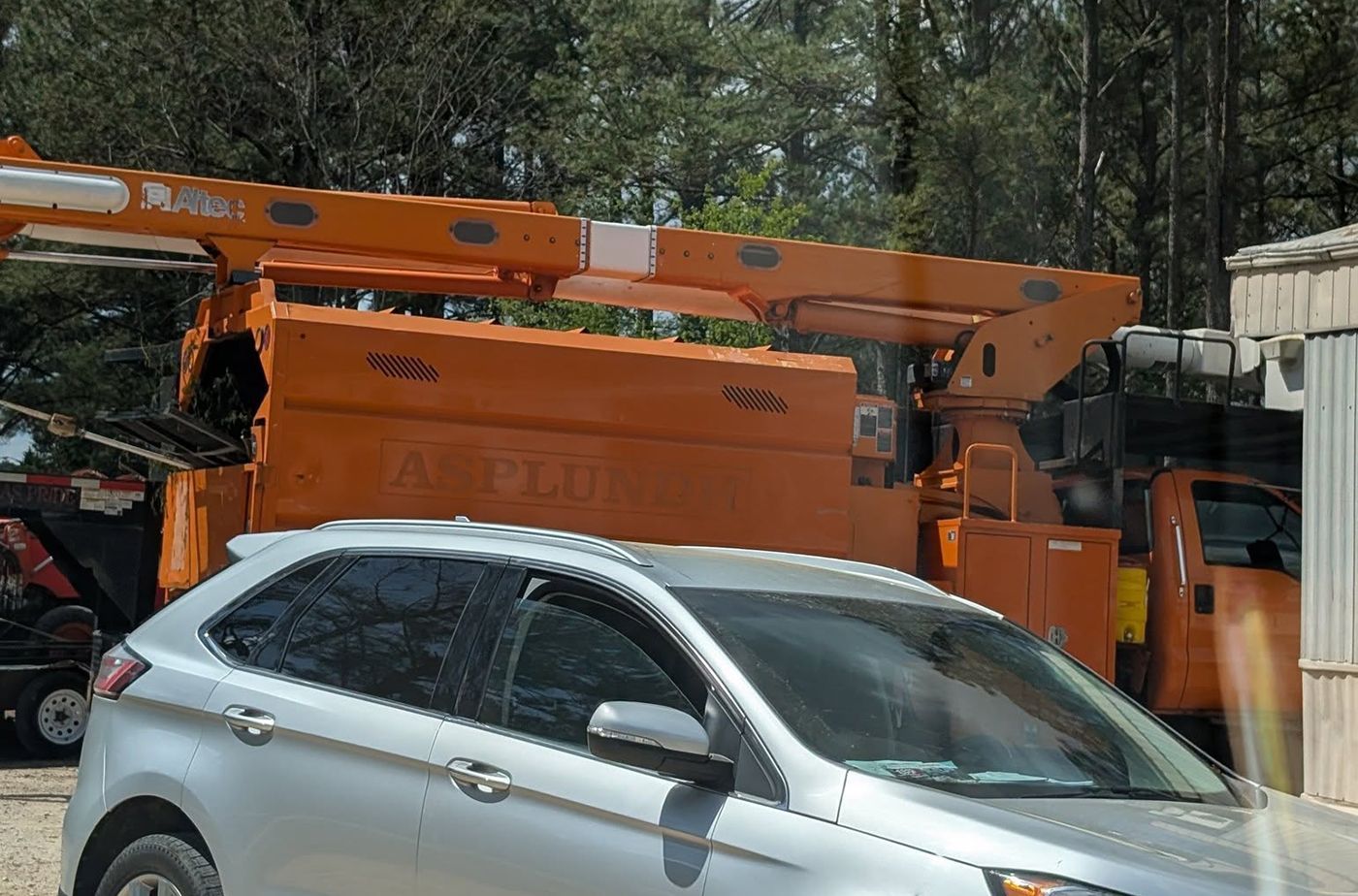 A silver car is parked in front of an orange truck