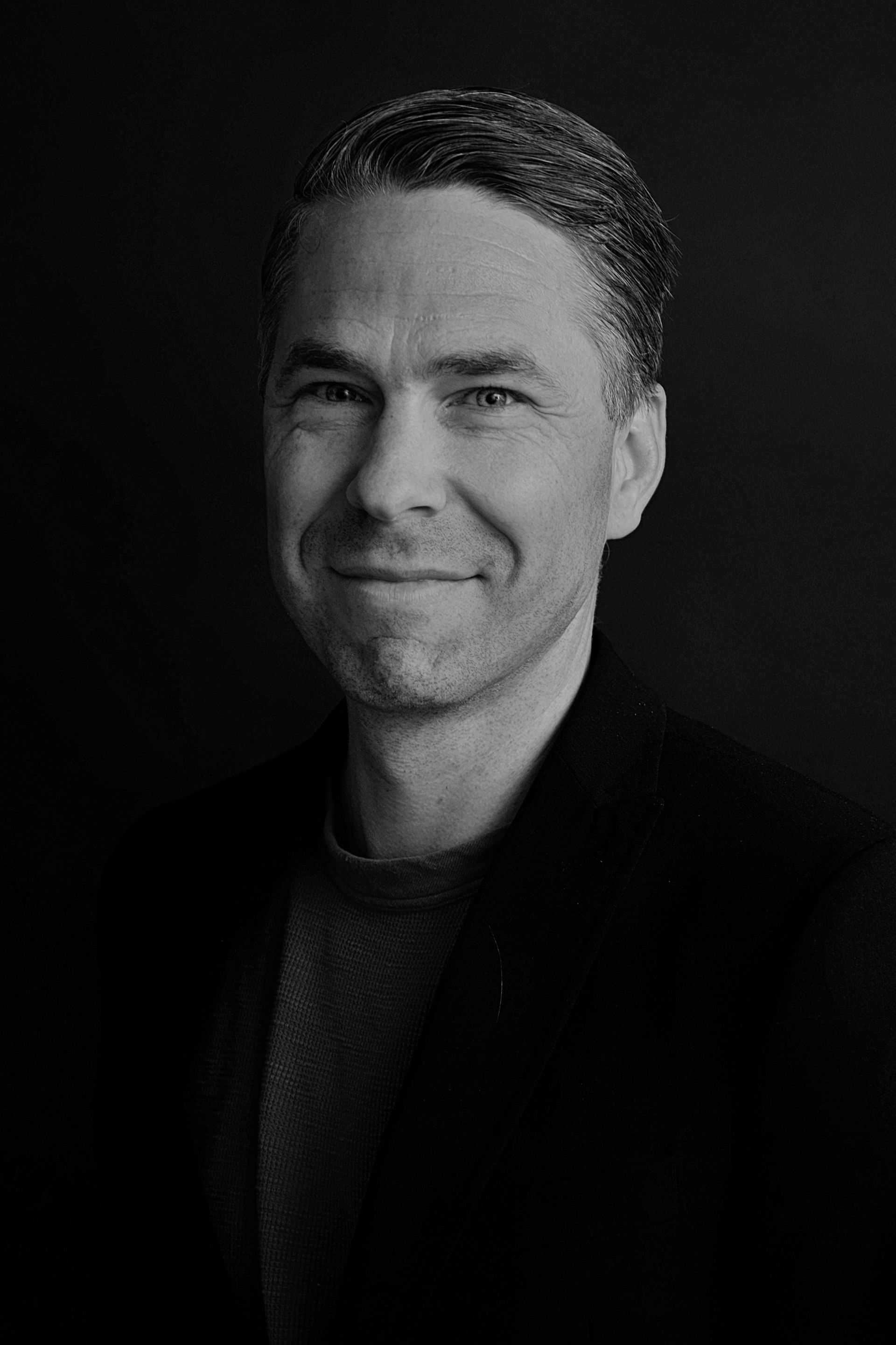 Moderne showroom van een autodealer met tentoongestelde auto's; groot scherm waarop een autoadvertentie wordt getoond; lichte, gepolijste vloeren.