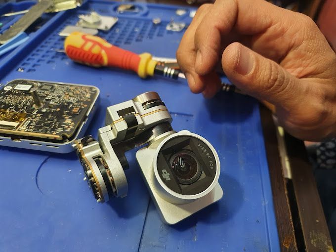 Una persona está arreglando una cámara con un destornillador.