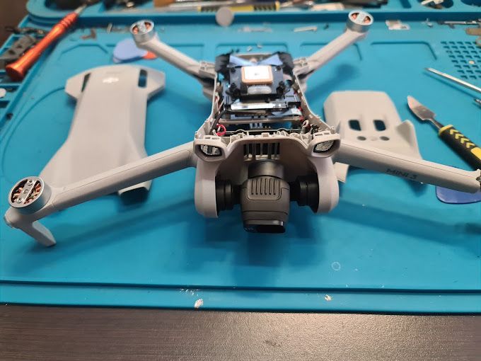 Se está reparando un dron sobre una alfombra azul.