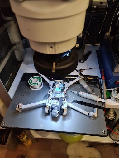 Se está reparando un dron bajo un microscopio sobre una mesa.