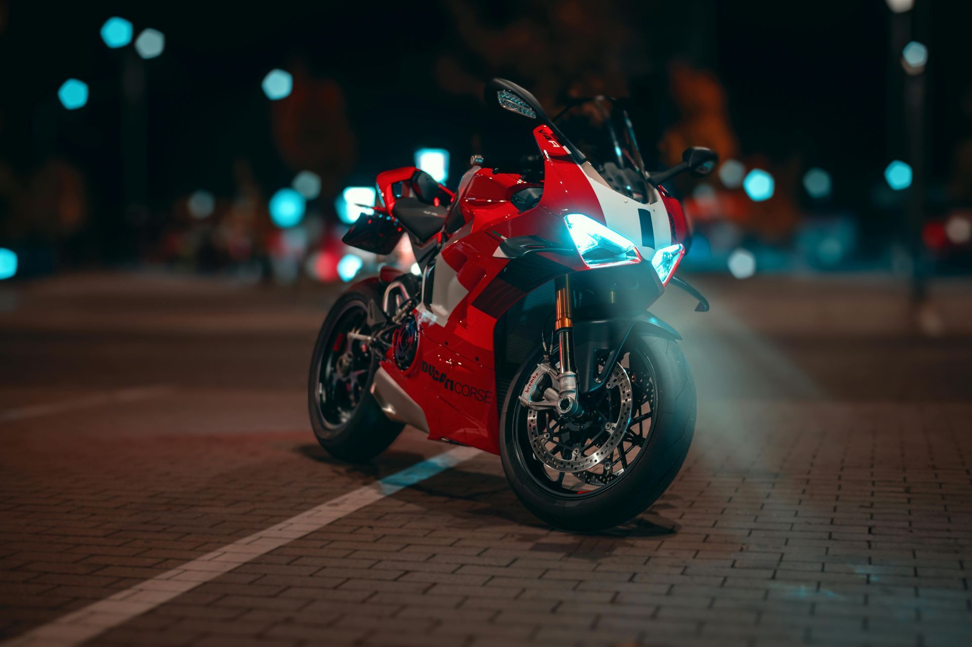Red sport motorcycle parked on brick, illuminated at night.