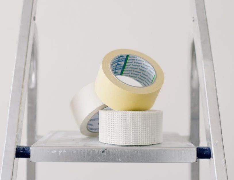 Three rolls of tape are stacked on top of each other on a ladder.