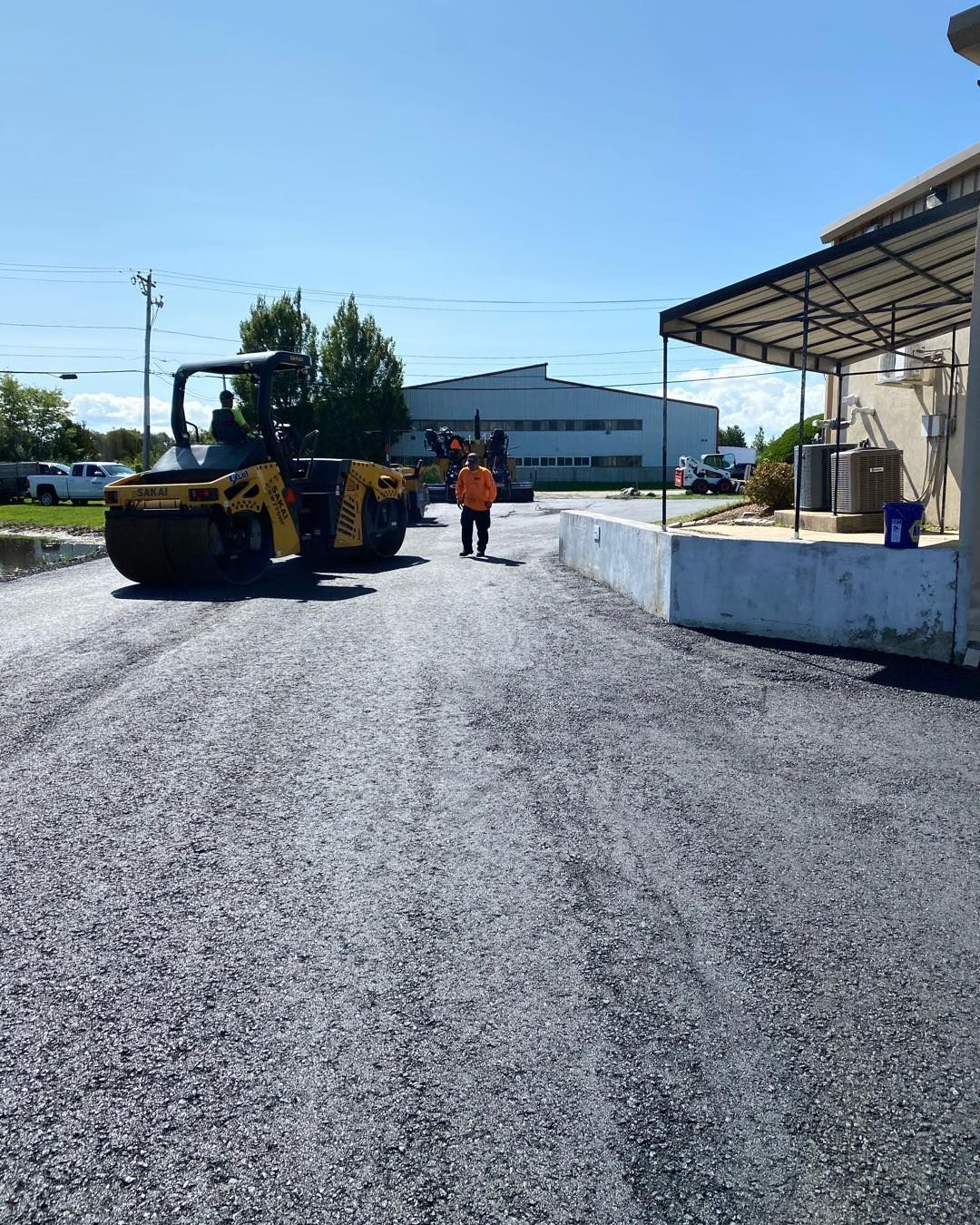 A couple of people are walking down a road next to a roller.