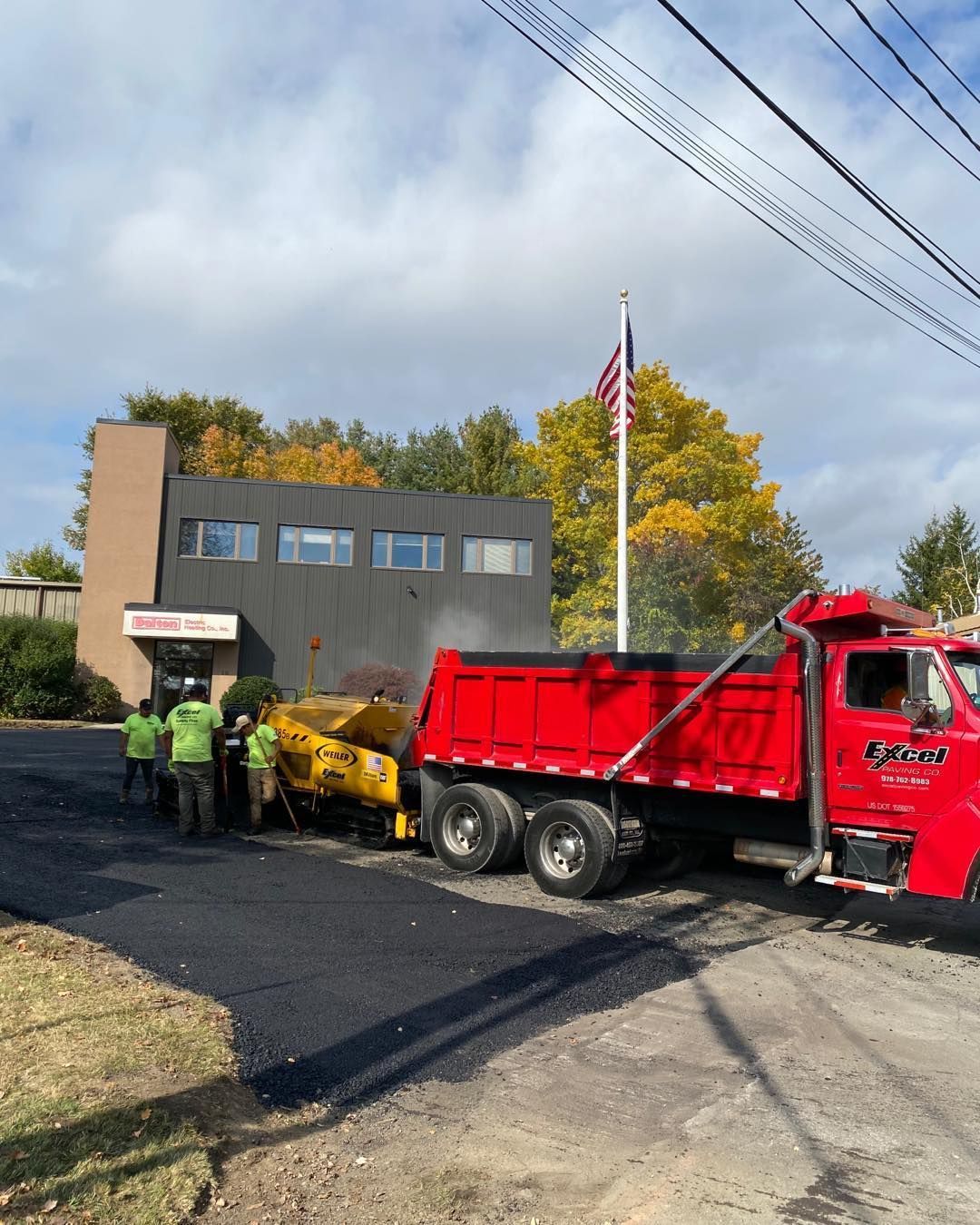 A red dump truck is parked in front of a building.