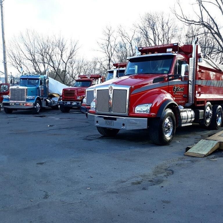A row of dump trucks are parked in a parking lot