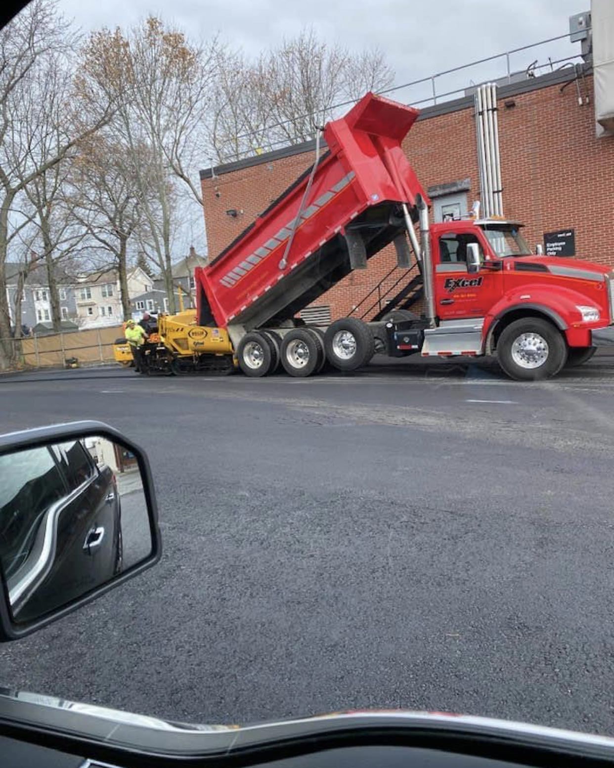 A red dump truck is parked in front of a brick building