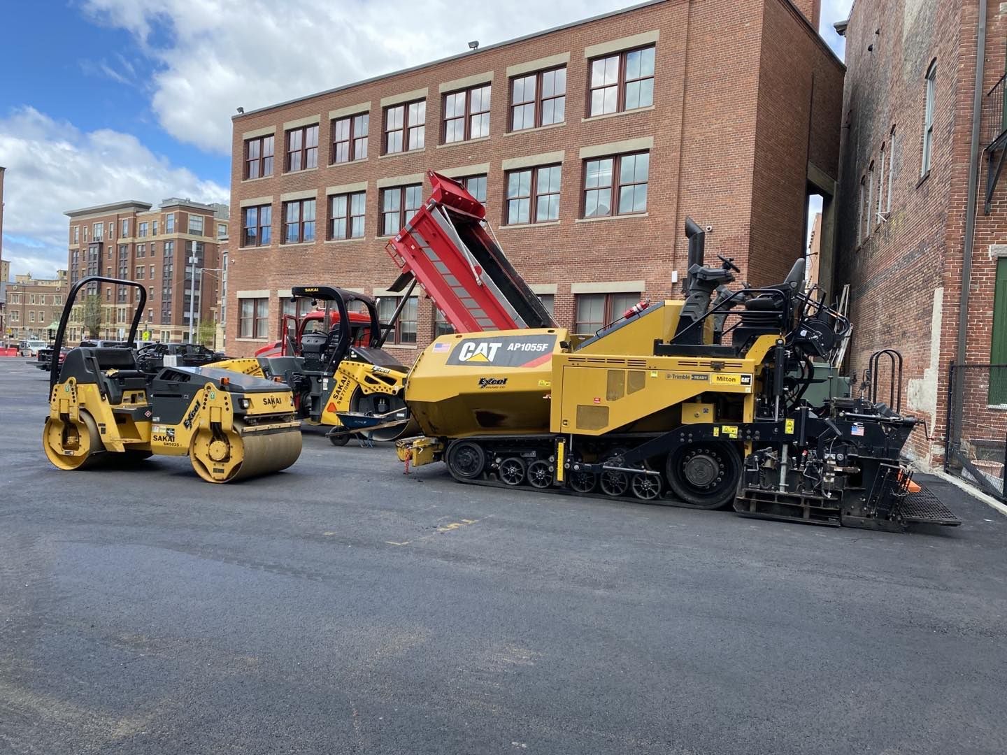 A group of construction vehicles are parked in front of a brick building.