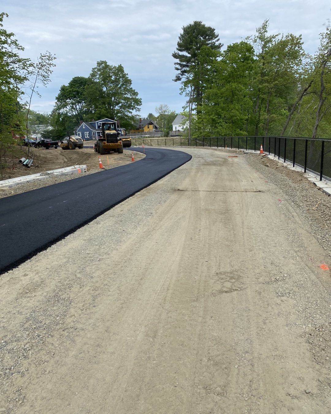 A road that is being paved with a bulldozer in the background