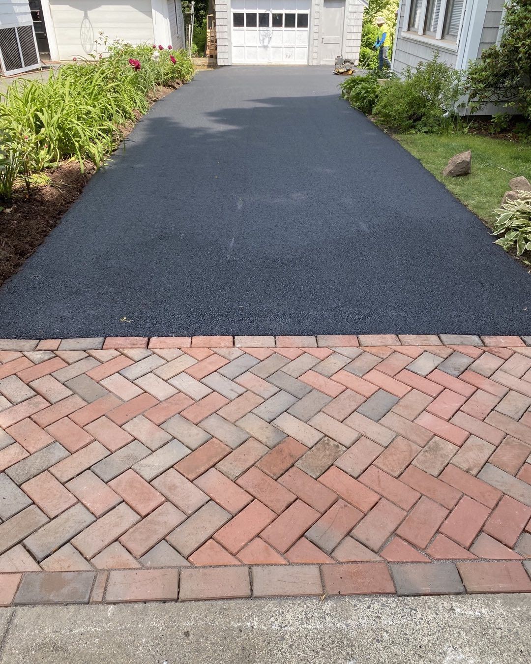 A driveway with a brick walkway leading to a garage.