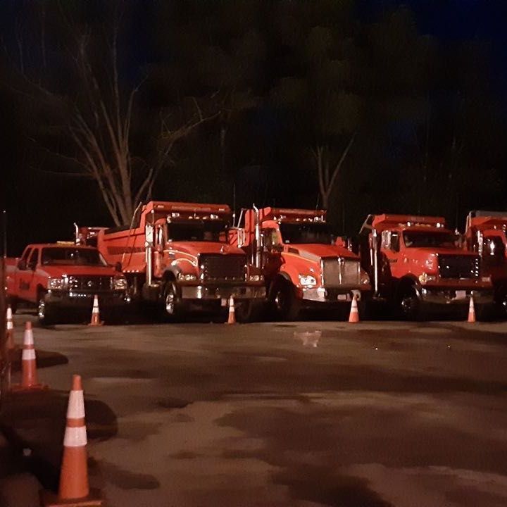 A row of red trucks are parked in a parking lot at night