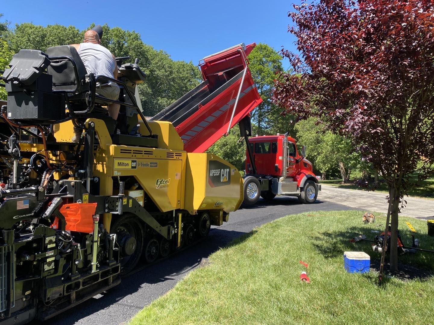 A yellow truck is driving down a road next to a red truck.