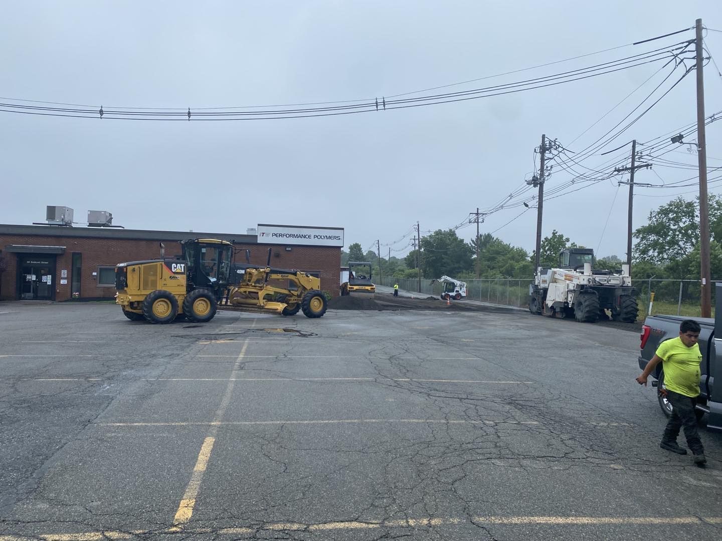 A man is standing in a parking lot next to a tractor.