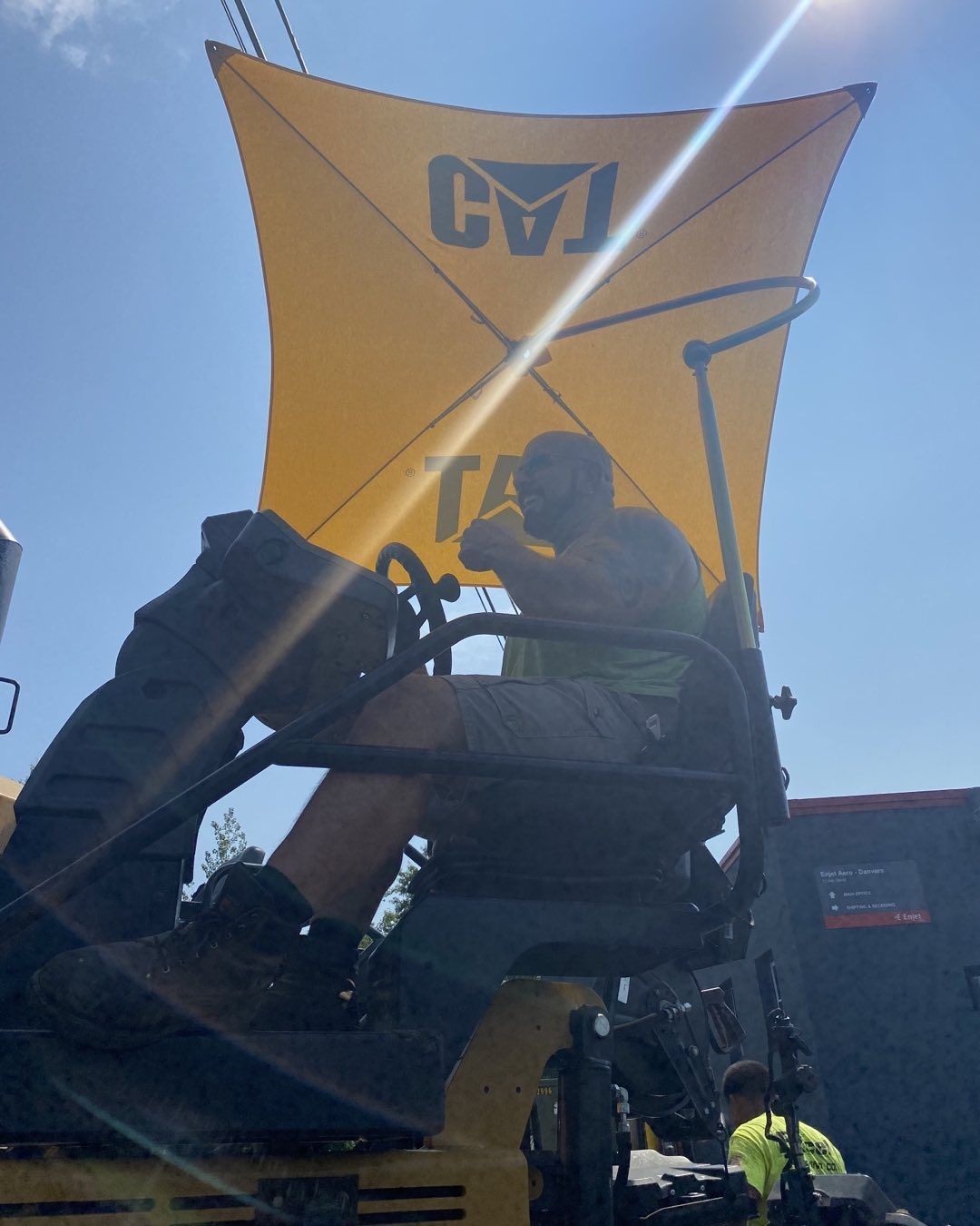 A man is sitting on a tractor under an umbrella that says cvj
