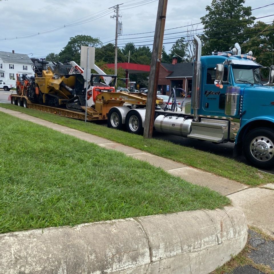 A blue semi truck is carrying a bulldozer on a trailer