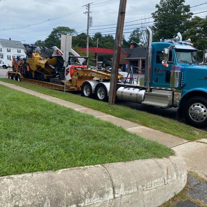 A blue semi truck is carrying a bulldozer on a trailer