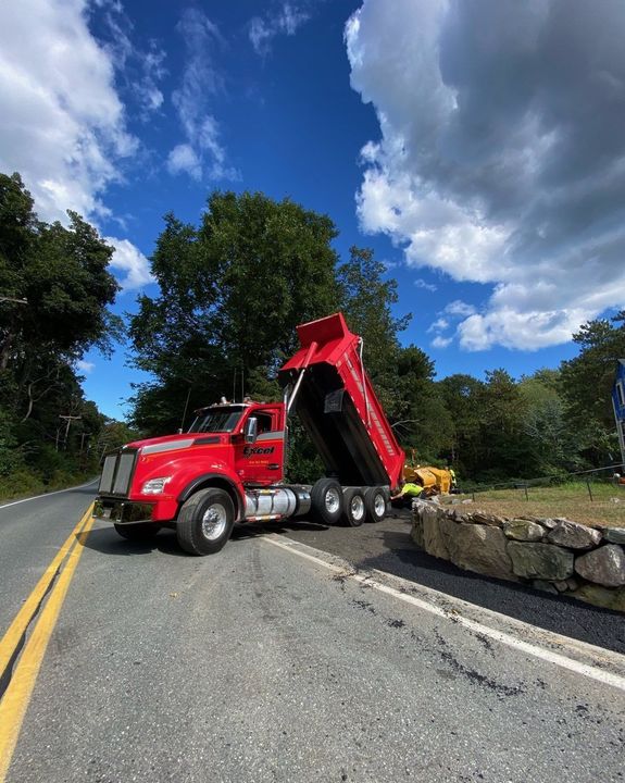 A red dump truck is parked on the side of a road.