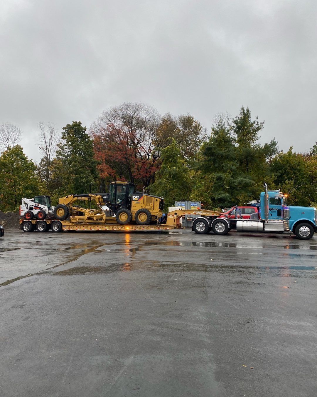 A truck is carrying a bulldozer on a trailer in a parking lot.
