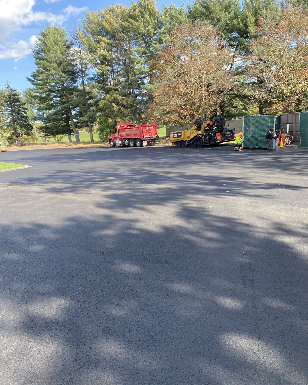 A red truck and a yellow forklift are parked in a parking lot.