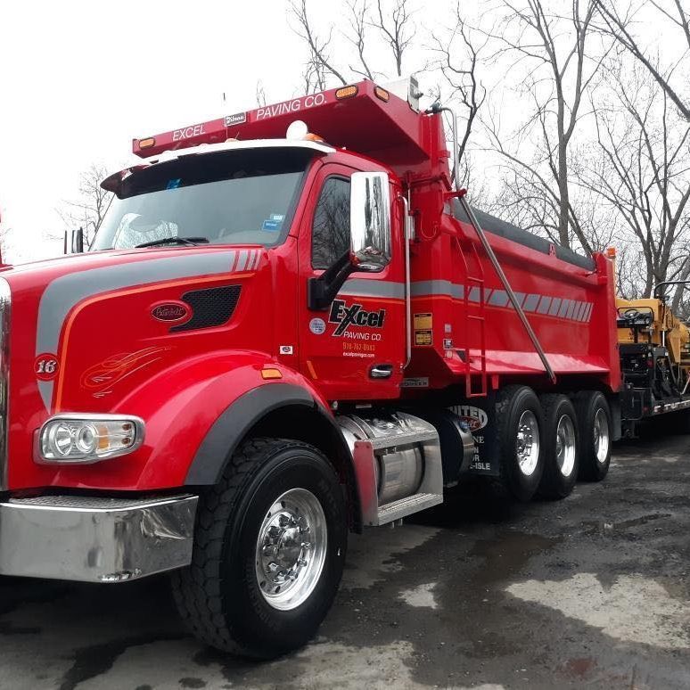 A red excal dump truck is parked in a parking lot