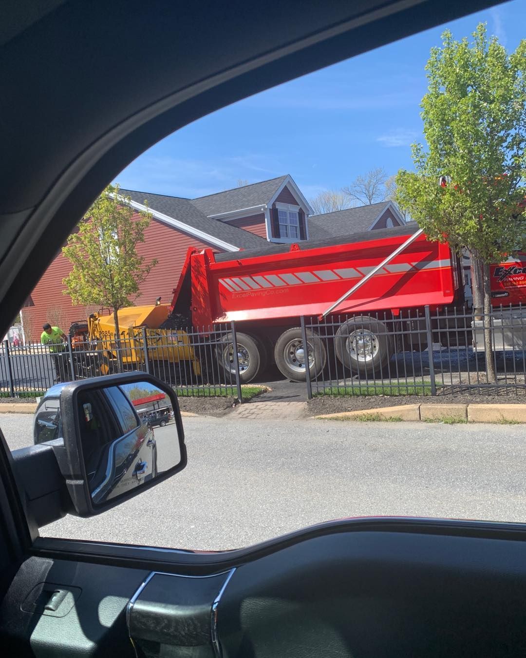 A dump truck is parked on the side of the road in front of a house.