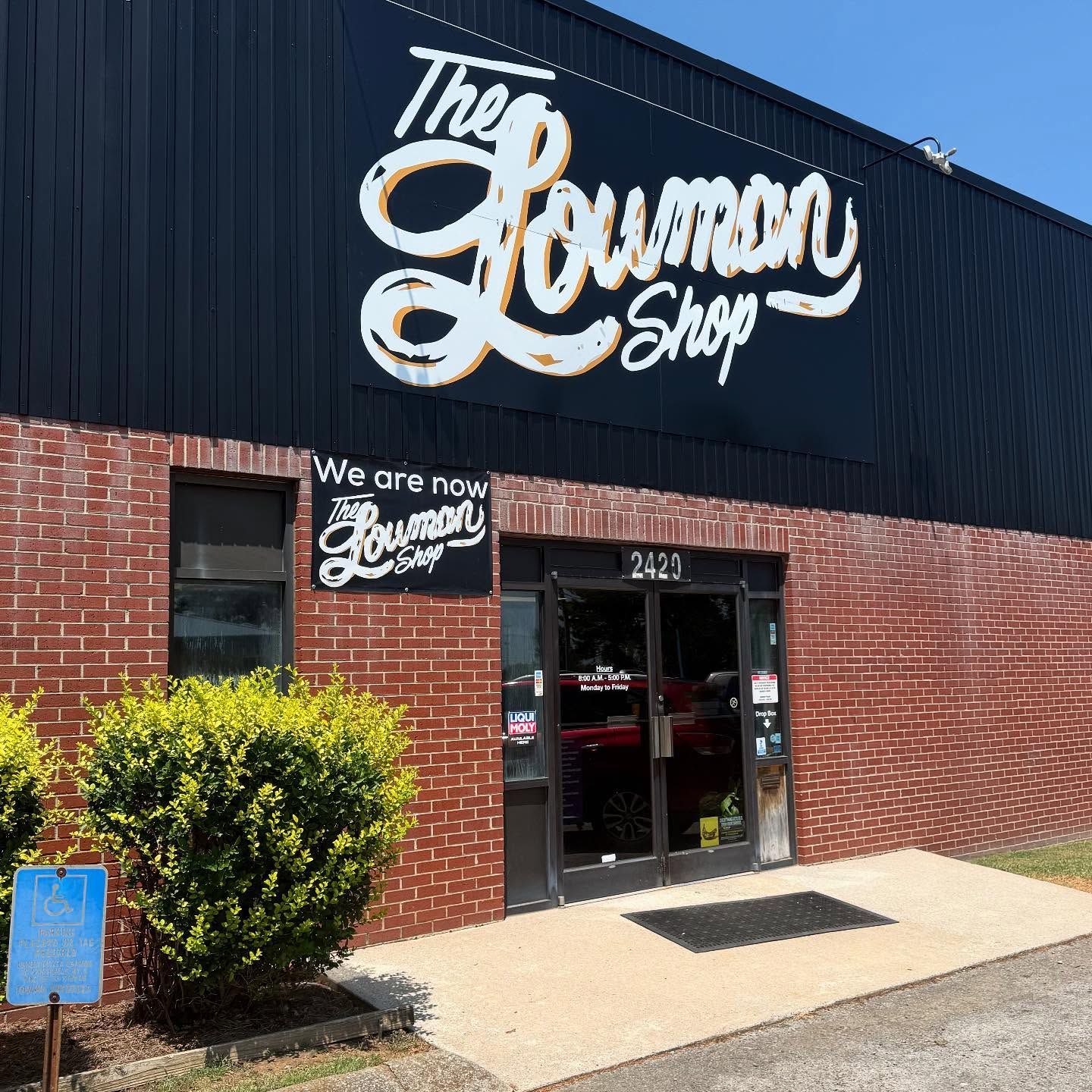 Front Entrance Of Auto Repair Shop With Brick Wall And Signage | The Lowman Shop
